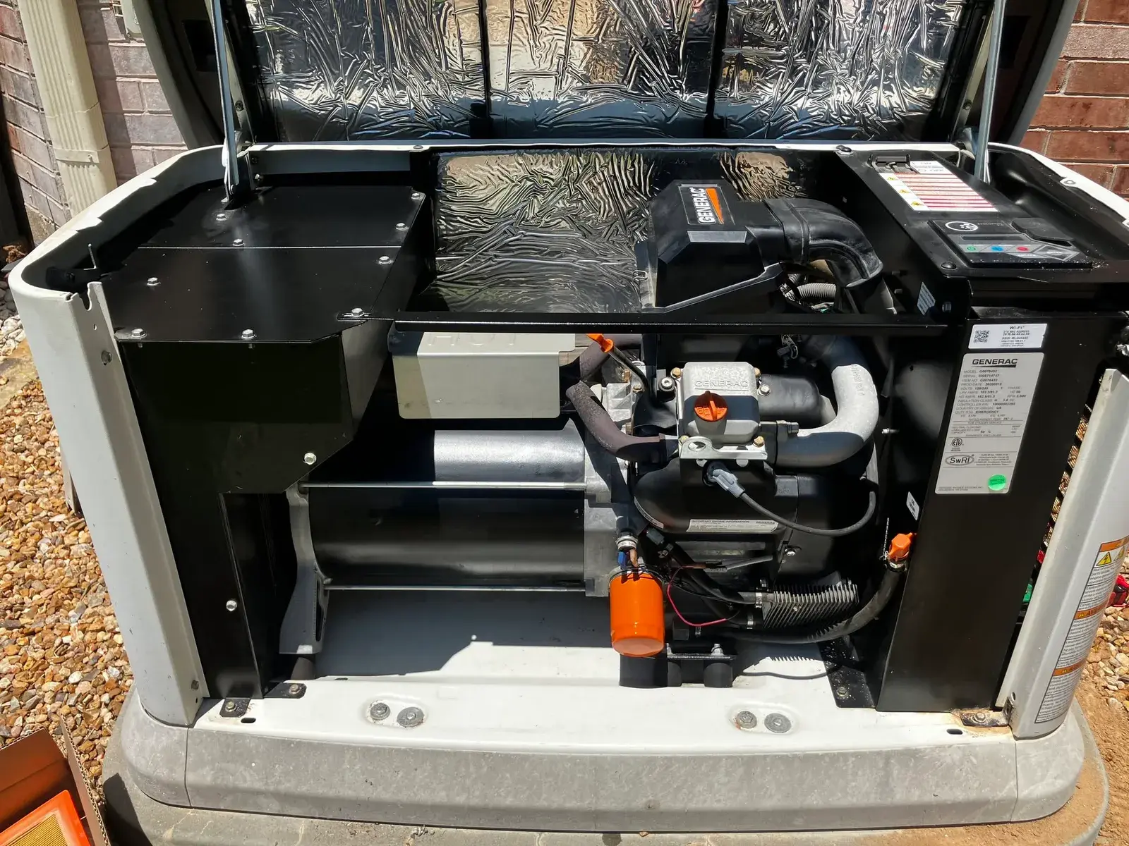 Generac home standby generator opened up for service beside a Houston brick home